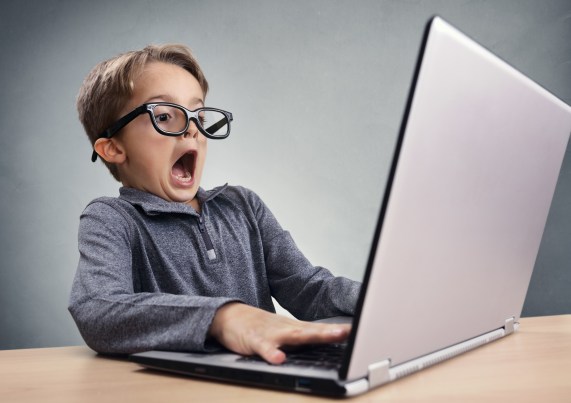 Shocked and surprised boy on the internet with laptop computer concept for amazement, astonishment, making a mistake, stunned and speechless or seeing something he shouldn't see